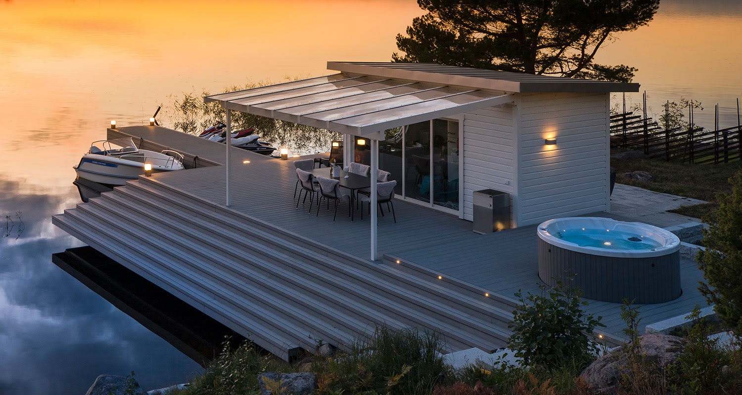 UPM ProFi Deck kivenharmaa terassilauta rantamökin terassilla, jossa auringonlasku ja ulkoporeallas