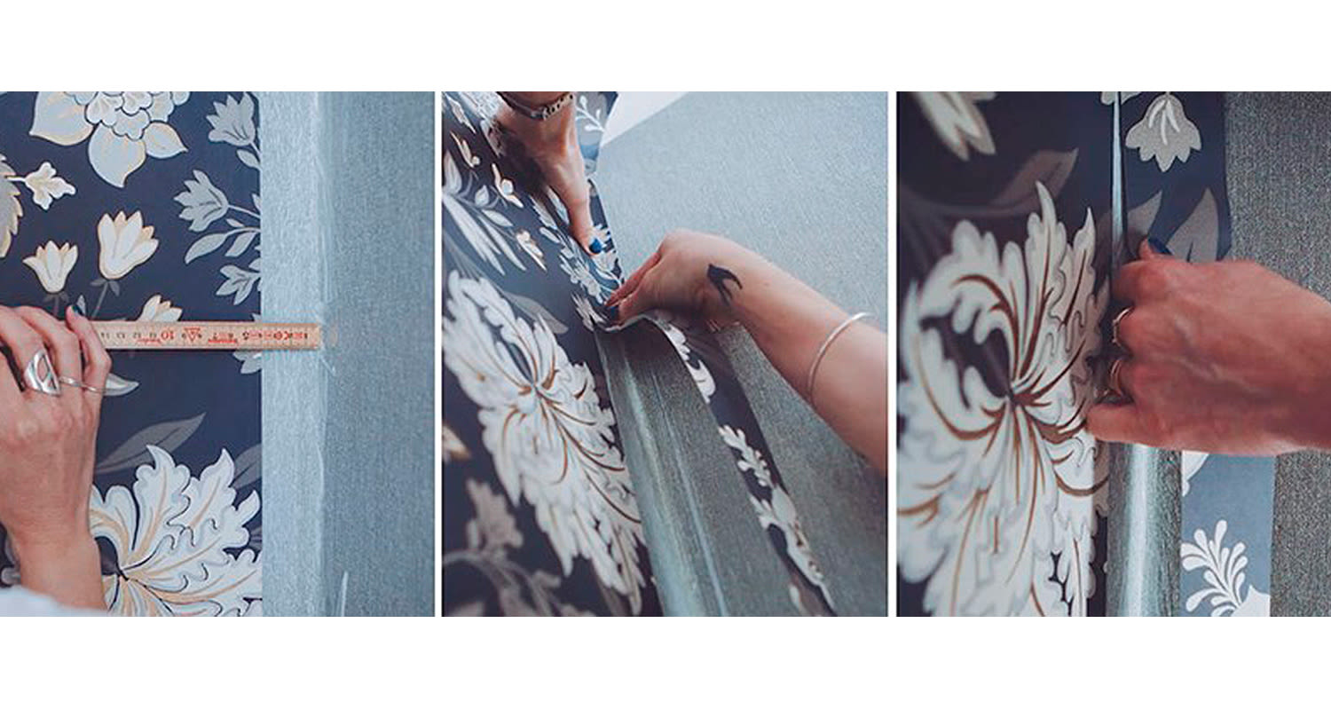 Kolmikuvassa kädet mittaavat ja asettelevat tummansinistä kukkatapettia harmaalle seinälle.