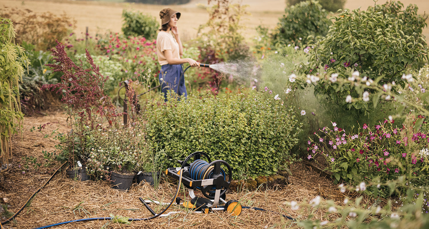 Nainen kastelemassa puutarhaa.