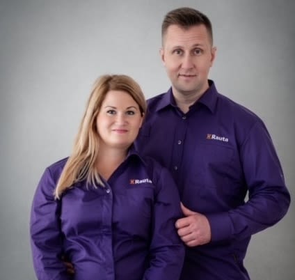 Pari K-Raudan violeteissä paidoissa harmaata taustaa vasten.