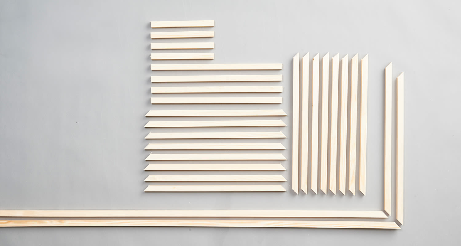 Vaaleat puulistat pituuden mukaan riveihin järjestettyinä harmaalla alustalla.