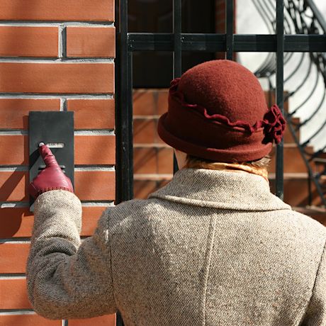 Nainen painaa punaisen tiilitalon ovikelloa