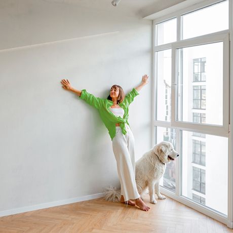 Nainen vaaleassa asunnossa koiran kanssa