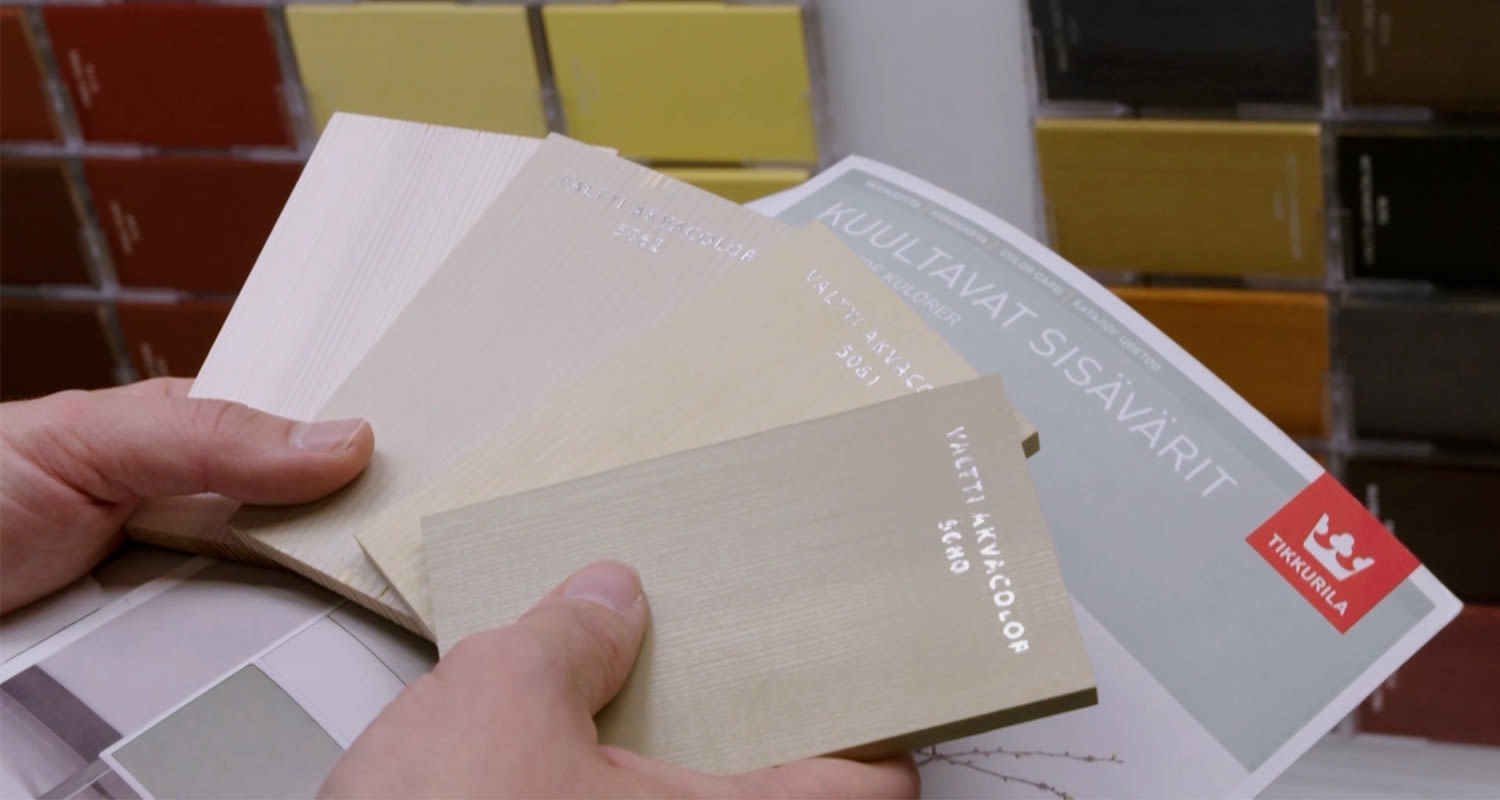 Kädet pitävät Tikkurilan vaaleiden neutraalien sisämaalisävyjen värikortteja.