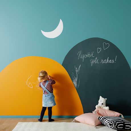 Pikkutyttö piirtää turkoosi-oranssiseinään, liitutauluun teksti 'Hyvää yötä rakas!'