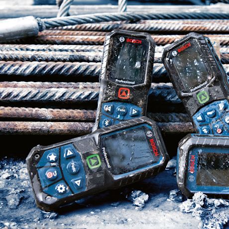 Pölyiset Bosch-etäisyysmittarit betonilattialla raudoitustankojen vieressä