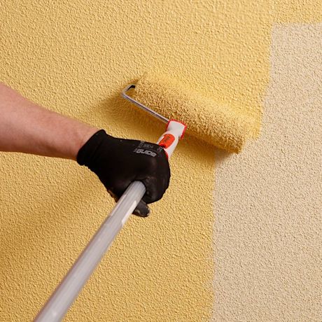 Seinää maalataan telalla keltaiseksi