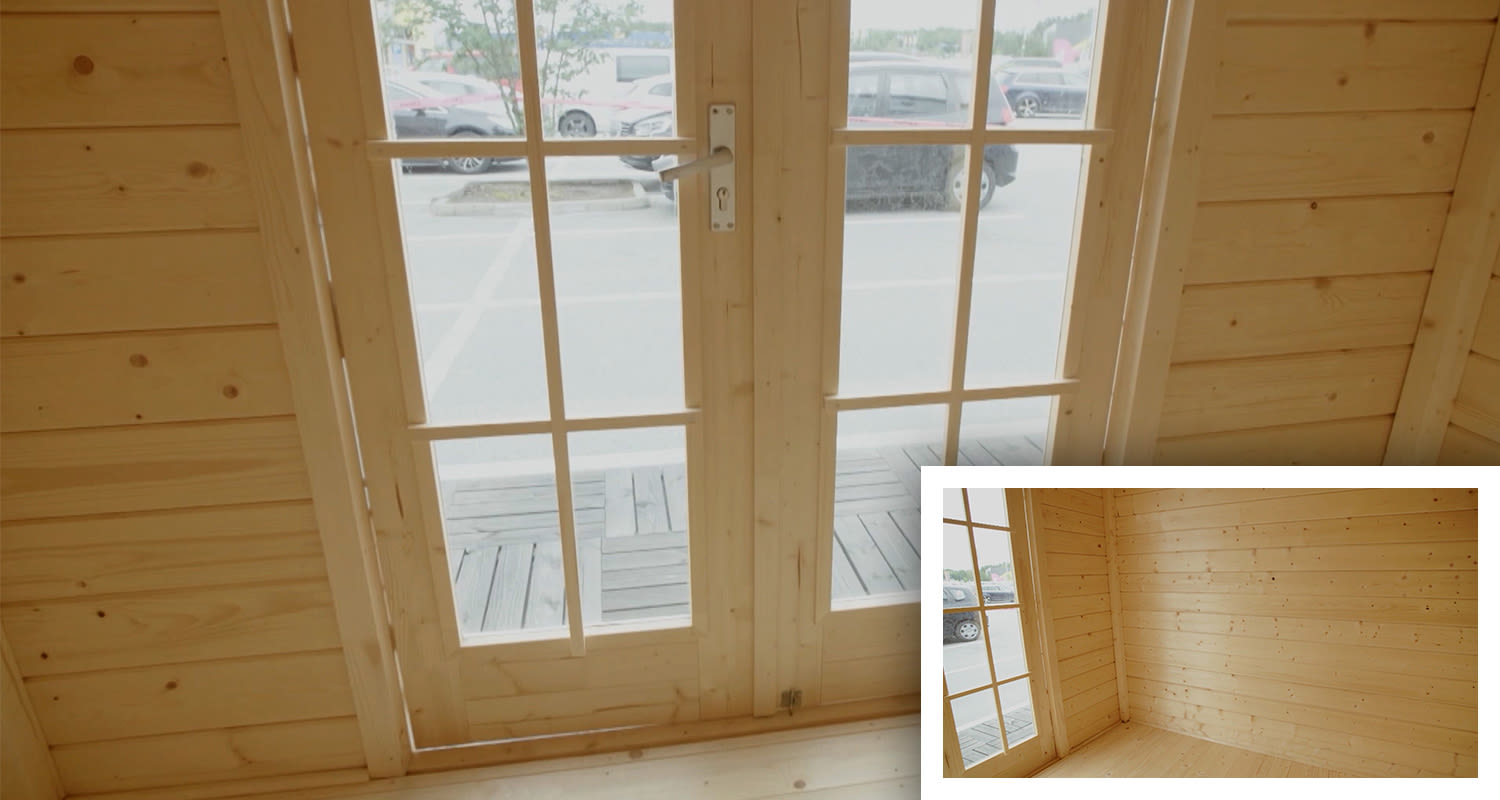 Vaaleapuisen mökkihuoneen sisätila, ruudulliset lasiovet aukeavat parkkipaikalle