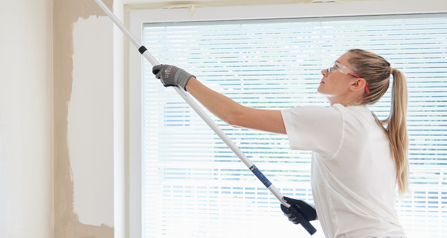 Nainen telaa kevyttasoitetta seinään.