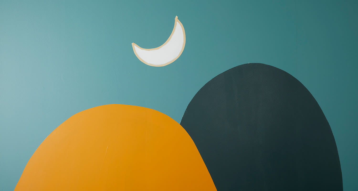 Turkoosilla seinällä abstrakti maalaus: oranssi kumpare, tummanharmaa kumpare ja valkoinen puolikuu.