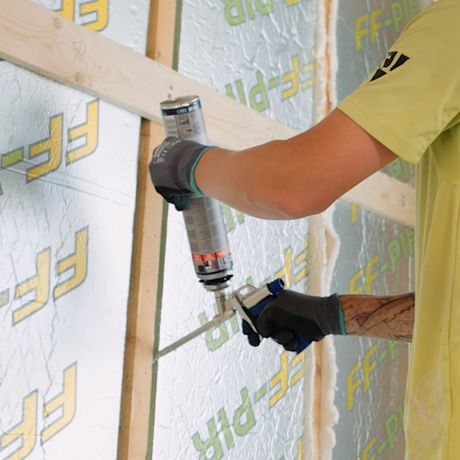 Mies tekee seinän eristämistä pir-levyllä.