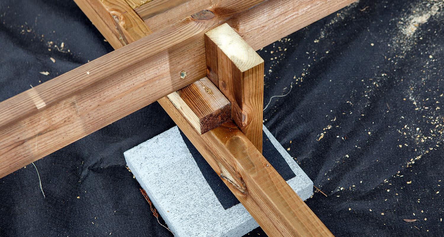 Ruskeat puiset palkit mustalla kankaalla betonikiven päällä.