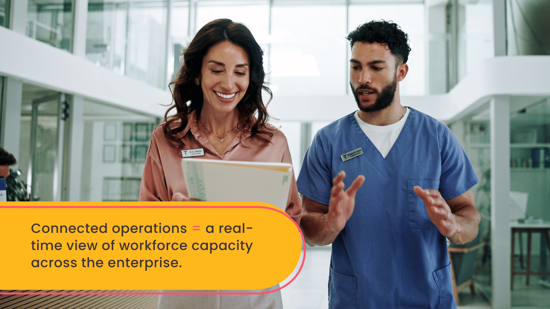 A CNO and an RN walking through a hospital corridor in discussion, representing collaboration on connected workforce operations, staffing efficiency, and coordinated hospital workforce management.
