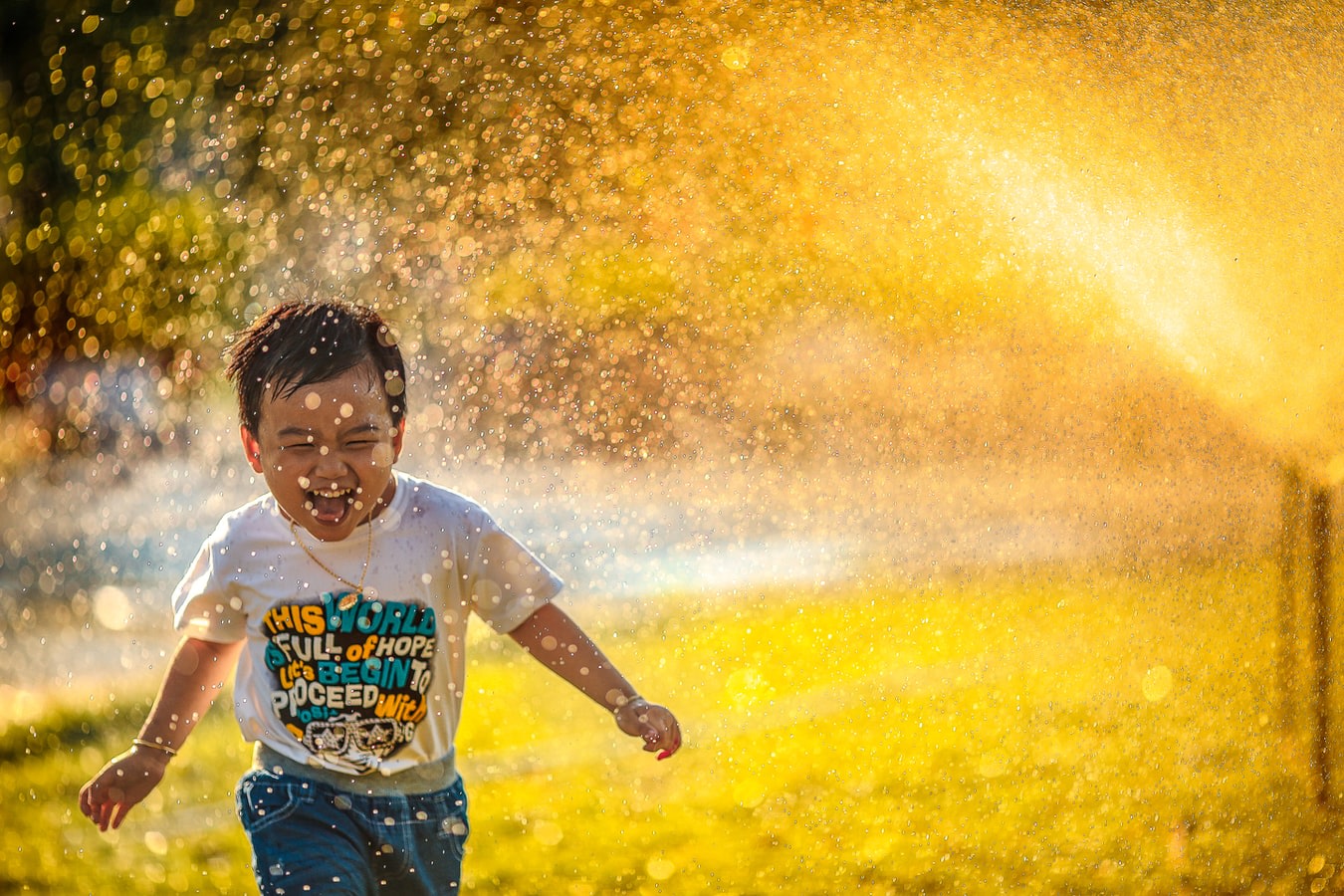 Child running in a water sprinkler