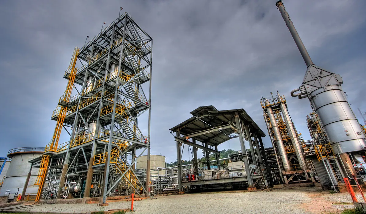 Large industrial processing plant with metal structures and equipment under a partly cloudy sky.