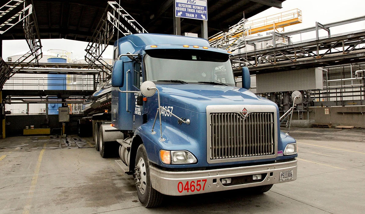A blue semi-truck parked at an industrial facility, ready for loading or transport.