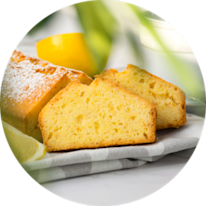 Sliced lemon cake on a plate, showcasing its moist texture and a fresh lemon.