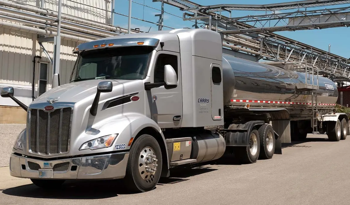 Newly designed silver semi-truck parked near industrial buildings on a clear day, showcasing the front view clearly.
