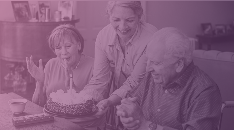 An older woman places a birthday cake in front of an man