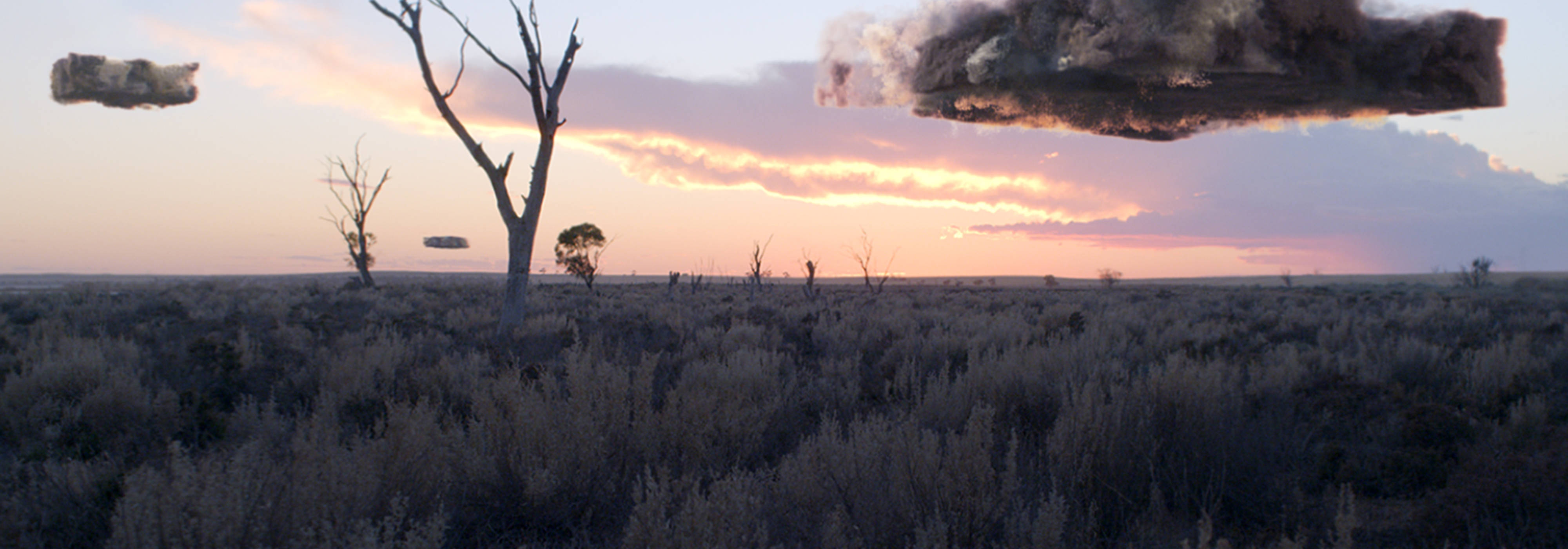 Square-shaped chunks of air pollution above a grassy outback landscape at sunrise.