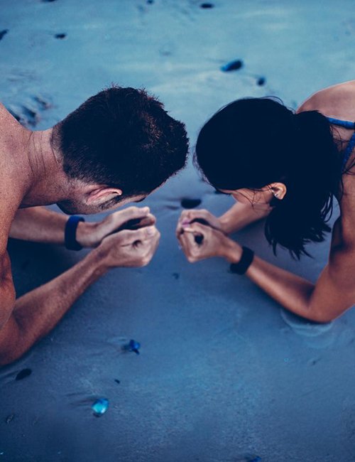Image of a man and woman doing planks on a beach.