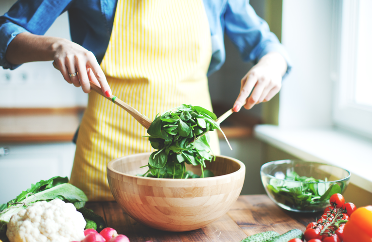 Woman wearing apron preparing a meal in her kitchen.