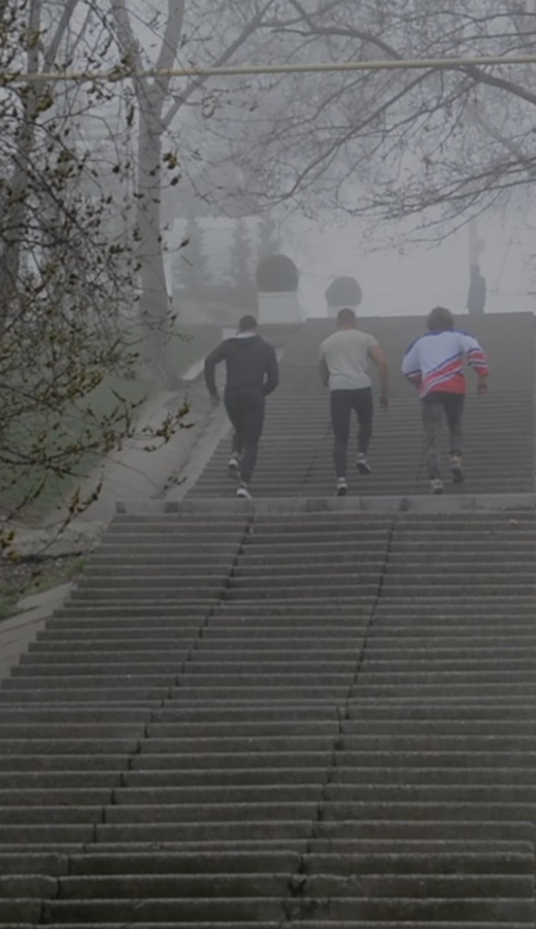 Three men running up park steps.