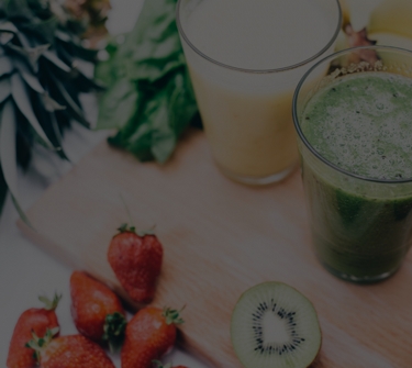 Fresh fruit and vegetables next to glasses of healthy drinks.