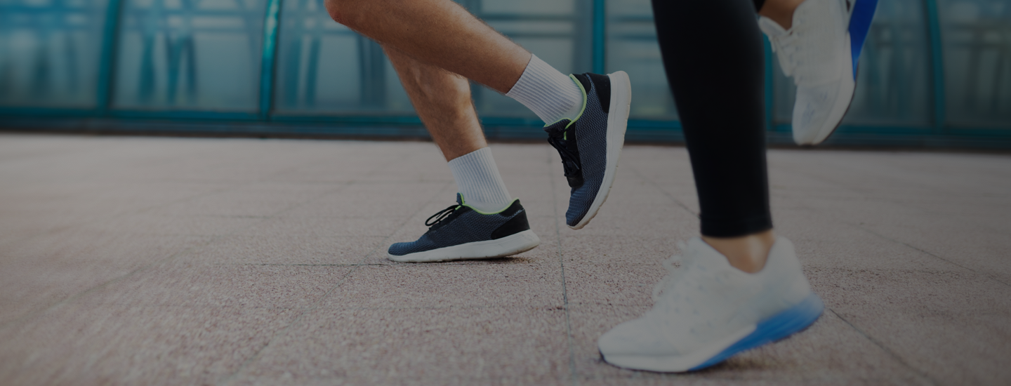 Two people running on pavement with focus on legs