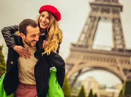 Coppia felice a Parigi, ragazza bionda con cappello francese rosso in spalle al ragazzo, sullo sfondo la Tour Eiffel