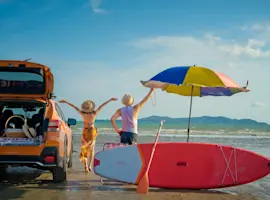 Viaggi vacanza al mare, ragazzi sulla spiaggia con ombrellone, tavola da surf e auto
