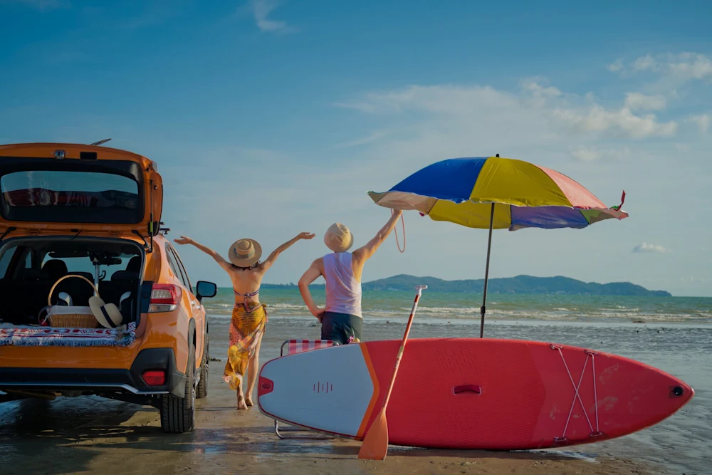 Viaggi - Vacanze estive dark Viaggi vacanza al mare, ragazzi sulla spiaggia con ombrellone, tavola da surf e auto