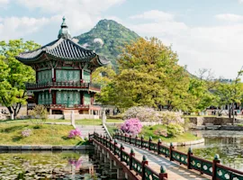 Corea del Sud - pagoda tipica su in isola all'interno di un lago, con un ponte antico che la collega alla terra ferma. Alberi e fiori tutti in torno al laghetto