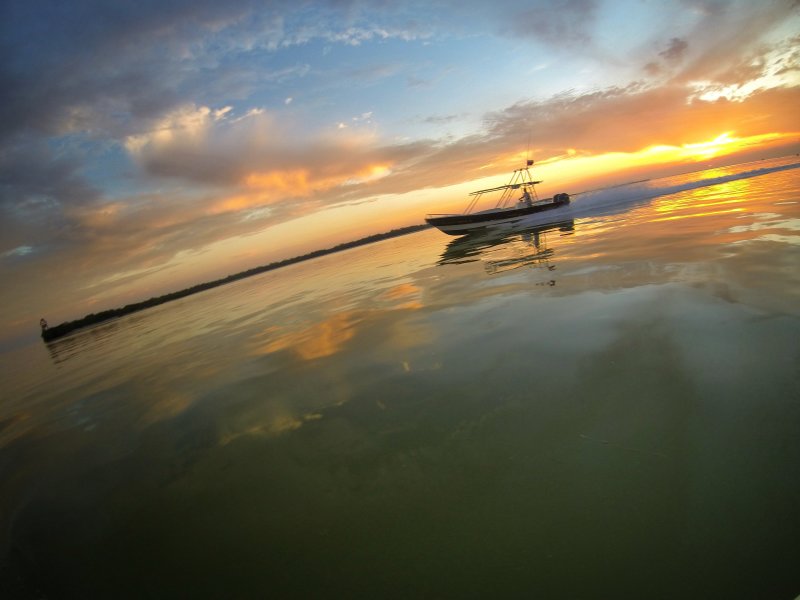 Tour boat passes by Isla Passion in Holbox with the sunrise in the back