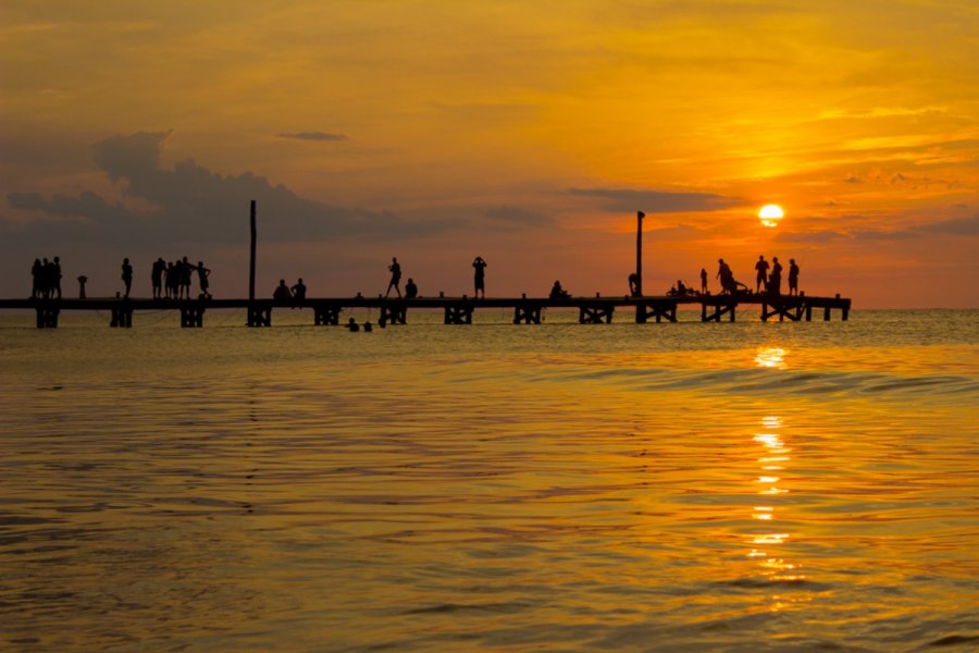 Holbox Sunset silhouettes tourists and locals on the pier with a rich orange glow