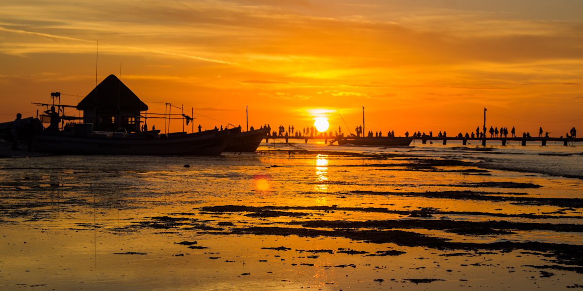 Holbox Sunset silhouettes tourists and locals on the pier with a rich orange glow