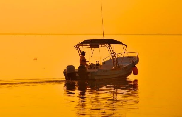 Amanecer en Holbox sobre la laguna Conil, un pescador en su lancha sale a trabajar