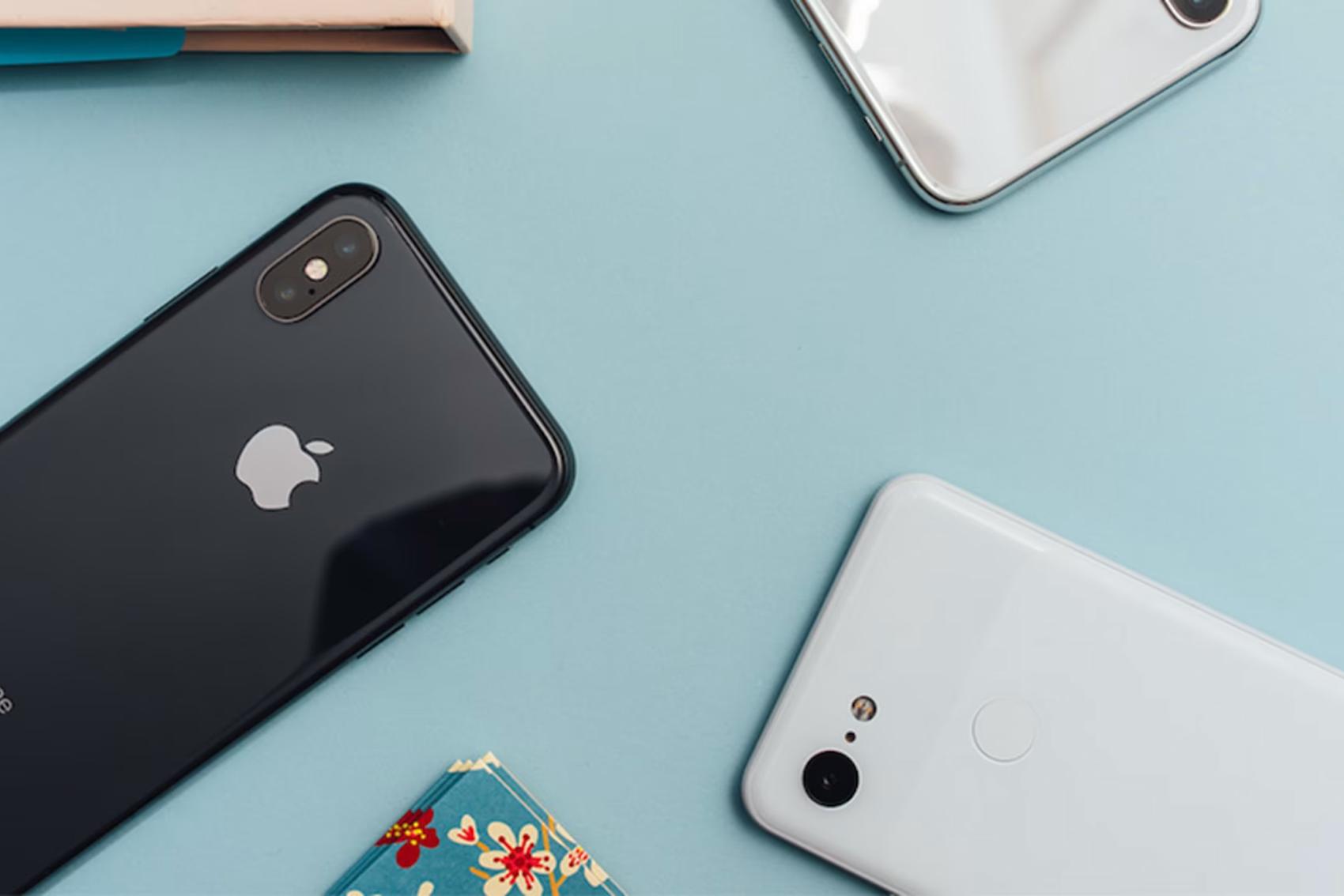 Närbild på flera mobiltelefoner på turkos yta