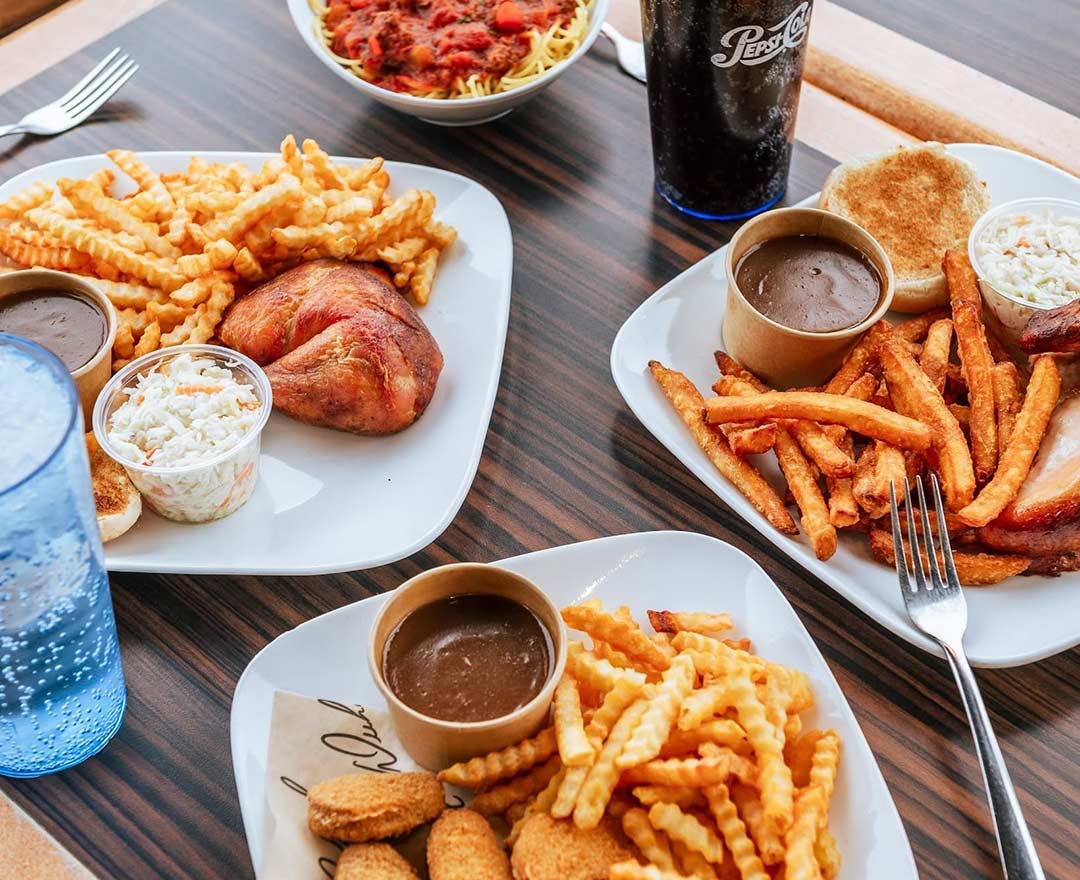 Une assiette club sandwich et pizzas en arrière plan