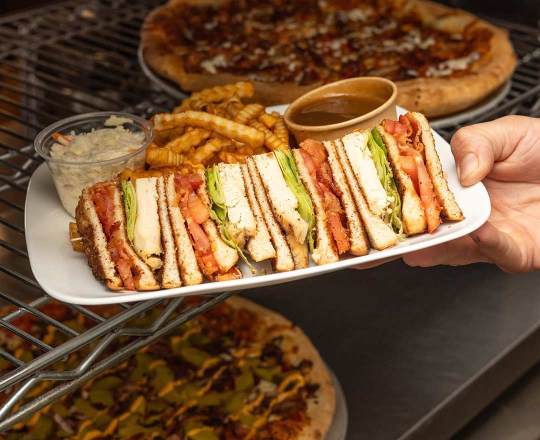 une femme qui mange une assiette avec brochette de poulet, salade, sauce et une liqueur