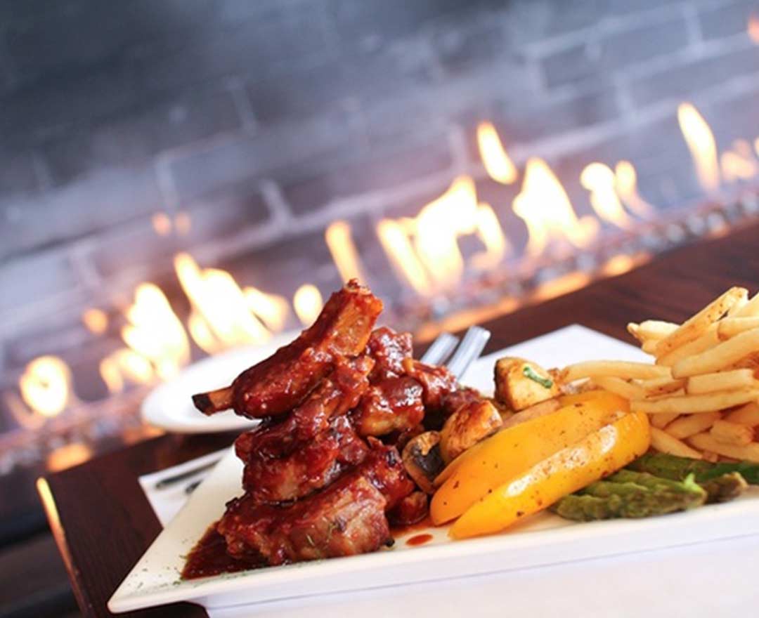 Un plat de côtes levées BBQ accompagné de frites, légumes grillés et petits pois