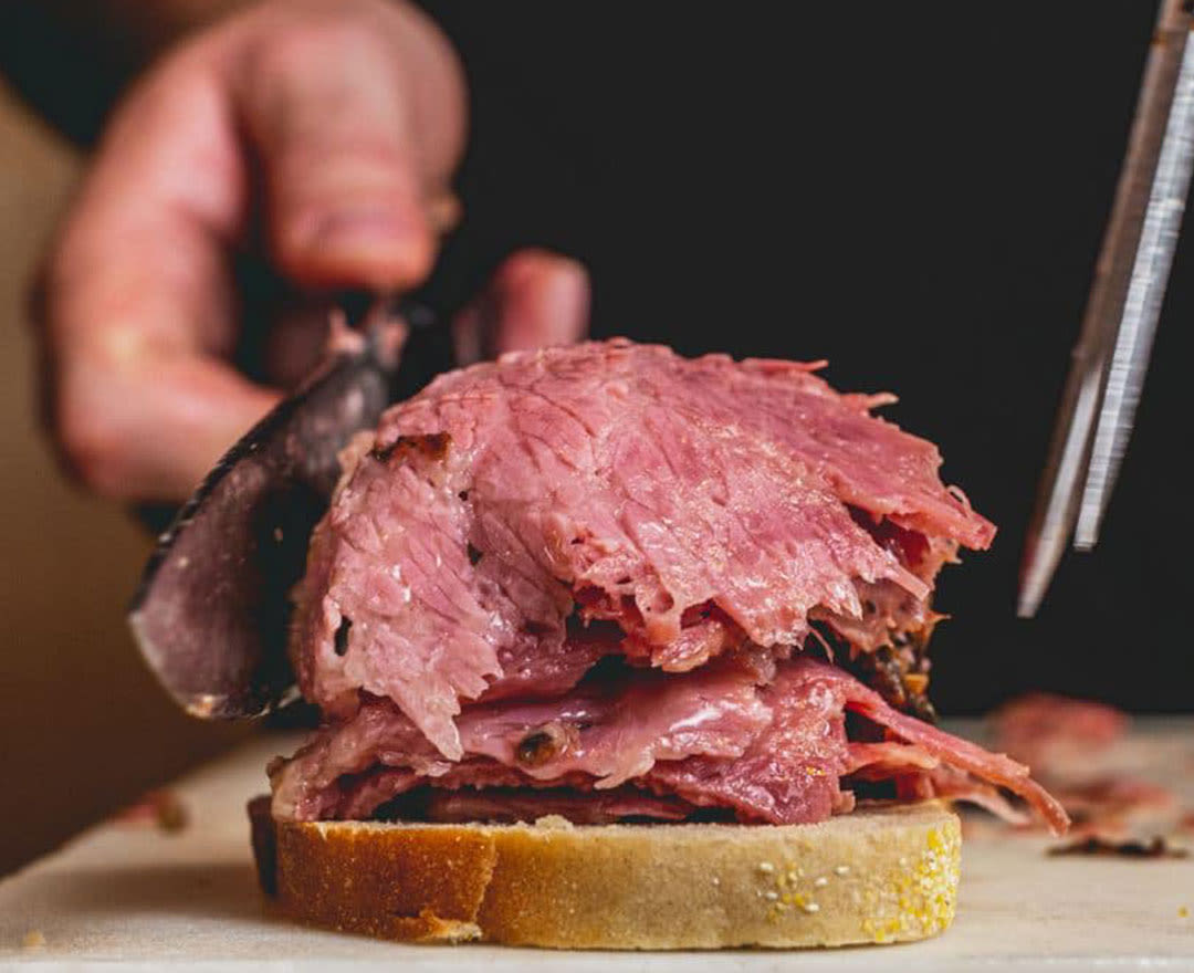 Une généreuse assiette de smoked meat tranché, accompagnée d'une salade César et d'une bière