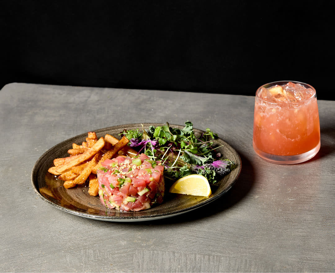 Une table généreusement garnie de plats colorés, de salades fraîches, de frites et d’un cocktail rafraîchissant.