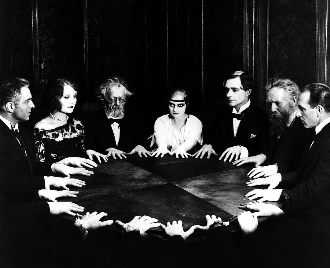 Mentaliste: Un groupe de personnes réunies autour d’une table éclairée à la chandelle pour une mystérieuse séance spirite.