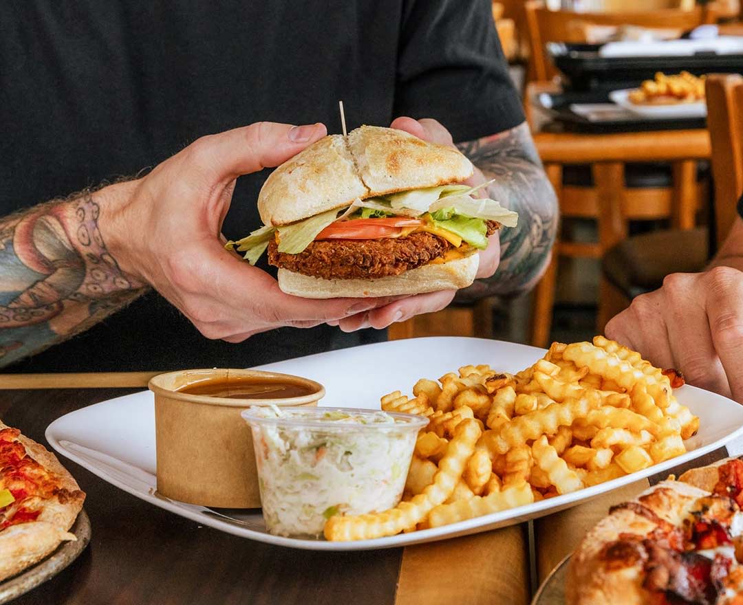 Une table remplie d'assiettes de: Pizza, club sandwich, frites, pépites de poulet, poulet et pita