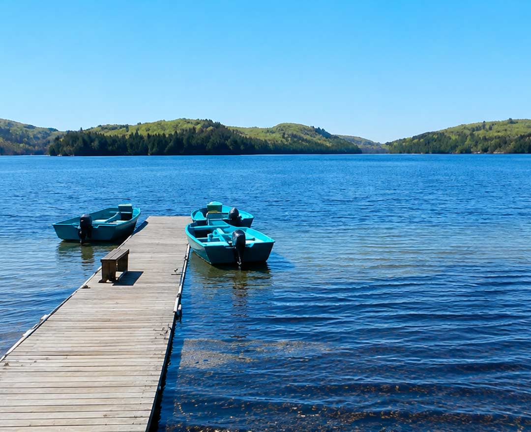chalet en bois rond dans la foret avec un quai sur le bord du lac