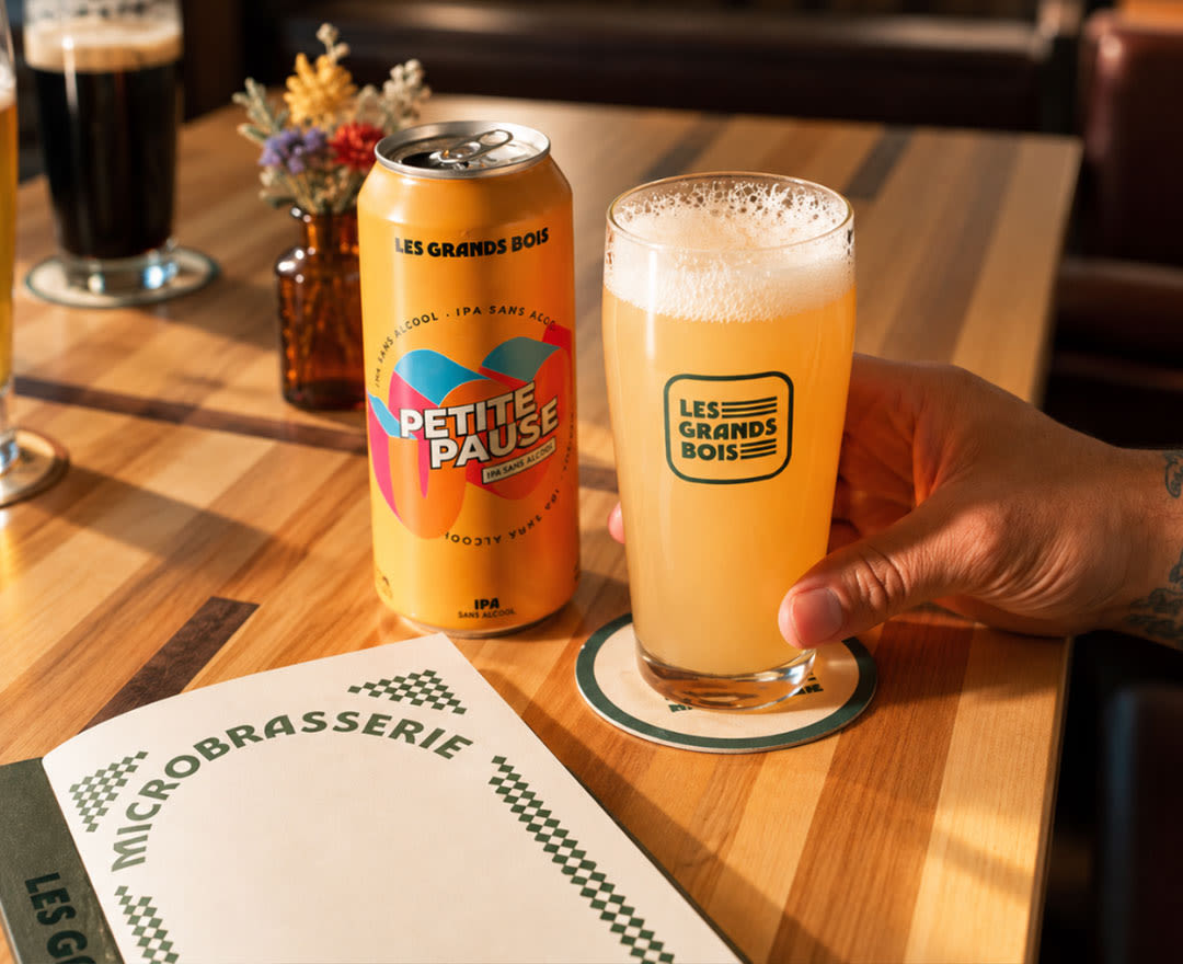 Une bière blonde coiffée d’une généreuse mousse est présentée sur une table en bois