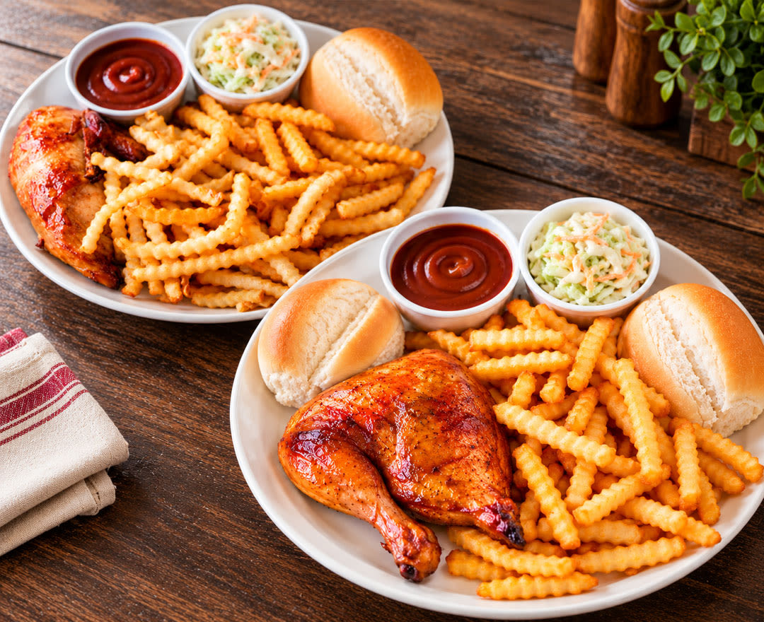 Deux personnes savourent un délicieux repas de poulet rôti accompagné de frites, de salade de chou et de pain, dans une ambiance chaleureuse à la maison.