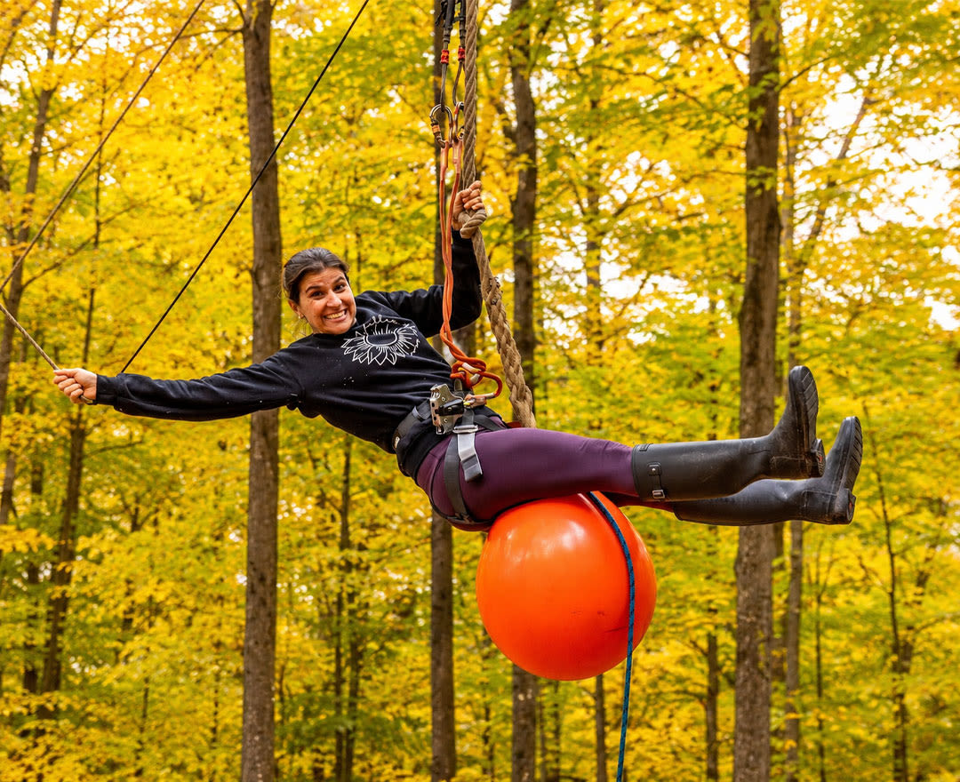 Extéria: Une personne s’amuse sur des parcours aériens au cœur d’une magnifique forêt aux couleurs d’automne.