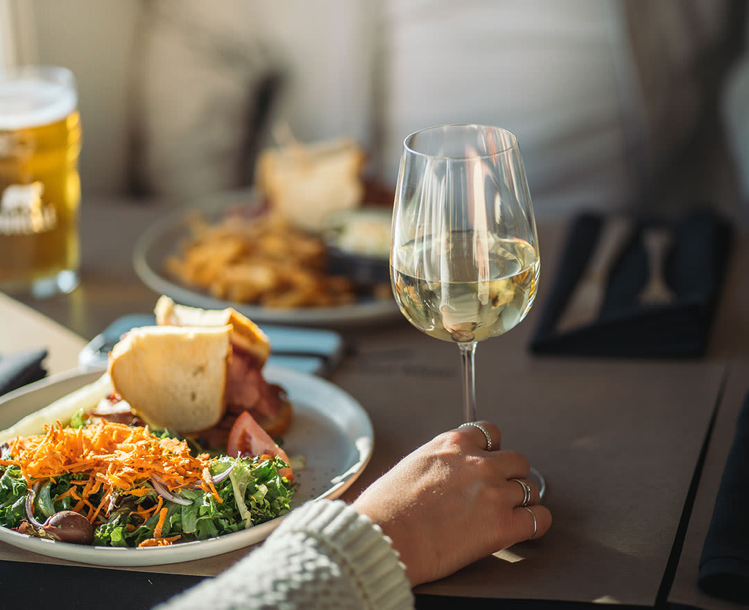 Deux femmes partagent un agréable repas au restaurant en trinquant avec un verre de vin blanc.